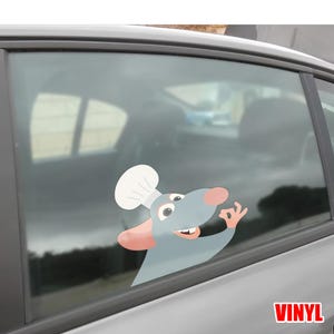 Puede incluir: Una calcoman&iacute;a de vinilo para coche con un chef de dibujos animados con un gorro blanco y haciendo el gesto de la mano de 'ok'. La rata es gris con la nariz y las orejas rosas. La palabra "VINYL" est&aacute; impresa en rojo.