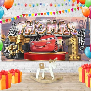 May include: A birthday party scene with a banner that says "THOMAS" and features a red race car. The scene includes balloons, checkered flags, golden trophies, and wrapped gifts. A wooden rocking horse and a light-up number one are also present.
