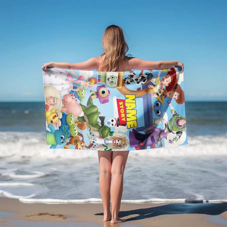 May include: A rectangular beach towel featuring a vibrant collage of animated characters from the Toy Story franchise, including Buzz Lightyear, Woody, and Jessie. The center displays the text NAME STORY in bold yellow letters on a blue background.