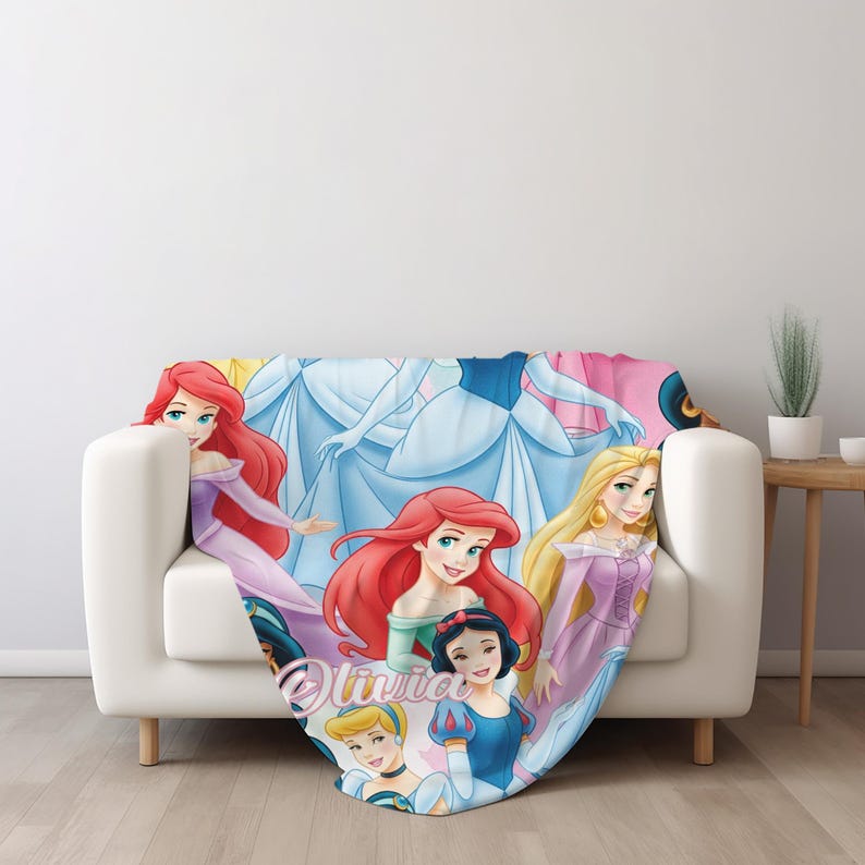 Pu&ograve; includere: Una morbida coperta con una stampa colorata di varie principesse animate con lunghi capelli fluenti e abiti vivaci. Il nome Olivia &egrave; stampato in corsivo al centro della coperta tra i vari personaggi raffigurati.