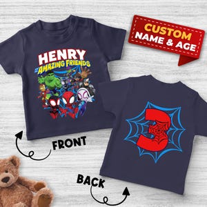 May include: A navy blue t-shirt featuring a graphic of various superhero characters and the text Henry and his Amazing Friends on the front, and a large red number 3 centered over a blue spiderweb design on the back, with a custom name and age tag.