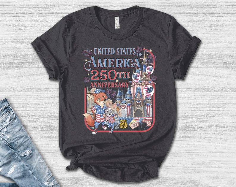 Puede incluir: Camiseta gris oscuro con un gr&aacute;fico colorido que celebra el 250 aniversario de los Estados Unidos de Am&eacute;rica. El dise&ntilde;o incluye personajes de dibujos animados, un castillo, fuegos artificiales y el texto "United States of America 250th Anniversary."