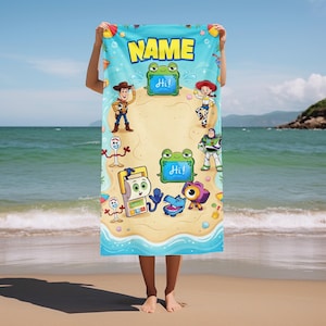 May include: A blue beach towel featuring cartoon characters and the word "NAME" in yellow. The towel has a sand and ocean theme with various characters and the word "Hi!" on a green frog.