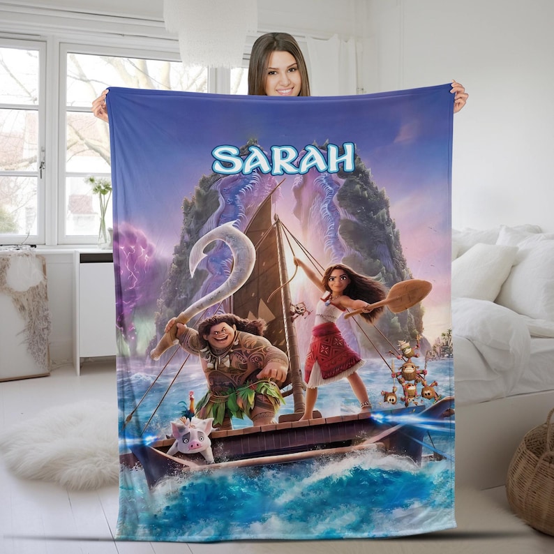 May include: A rectangular fleece blanket featuring a vibrant Moana-themed graphic with the name Sarah printed in blue at the top. The design depicts Moana and Maui on a wooden sailing boat on the ocean, accompanied by Pua and Heihei characters.