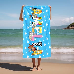 May include: A rectangular beach towel with a light blue background featuring a white cloud pattern. The name AMELIA is printed vertically in large block letters, each filled with patterns and characters inspired by the Toy Story franchise.