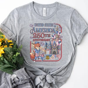 Puede incluir: Camiseta gris jaspeado con un gr&aacute;fico colorido que celebra el 250 aniversario de los Estados Unidos de Am&eacute;rica. El dise&ntilde;o incluye un zorro y un conejo de dibujos animados, un castillo y fuegos artificiales. La camiseta es de material suave.