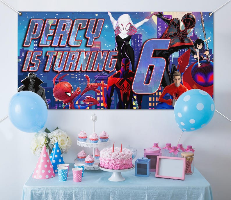 May include: A rectangular party banner featuring Spider-Man characters against a city skyline with the text PERCY IS TURNING 6. Below, a table holds a pink frosted cake, cupcakes on a tiered stand, party hats, and blue polka dot balloons.