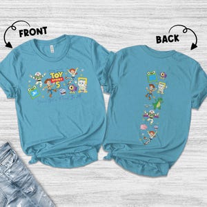 May include: A teal short-sleeve t-shirt shown from the front and back. The front features Toy Story 5 graphics with characters and the text You've Got A Friend In Me. The back displays a vertical column of various Toy Story character illustrations.