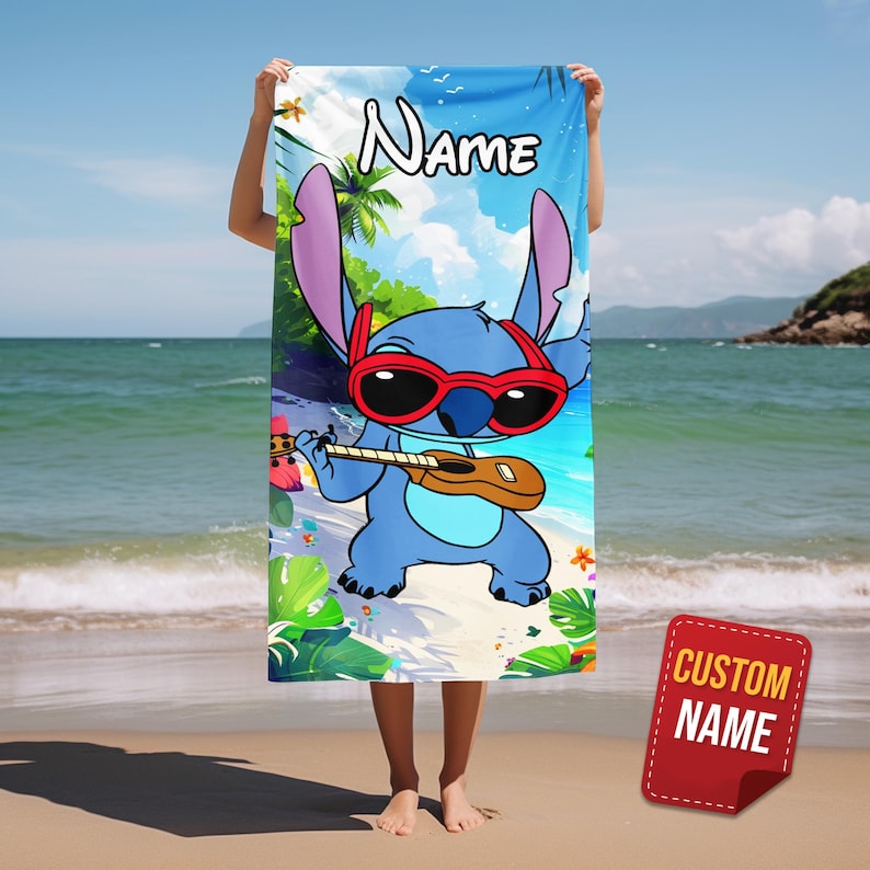 May include: A blue beach towel featuring a cartoon character wearing red sunglasses and playing a ukulele on a beach scene. The towel has the word "Name" at the top and a "Custom Name" tag.