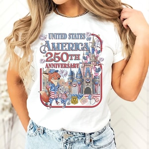 Puede incluir: Camiseta blanca con un gr&aacute;fico colorido que celebra el 250 aniversario de los Estados Unidos de Am&eacute;rica. El dise&ntilde;o incluye personajes de dibujos animados, un castillo, fuegos artificiales y el texto "UNITED STATES OF AMERICA 250TH ANNIVERSARY".