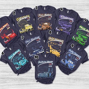 May include: A collection of ten dark navy blue short-sleeve t-shirts, each featuring a unique character graphic from the movie Cars. The designs include Lightning McQueen, Luigi, Tow Mater, Ramone, Chick Hicks, Finn McMissile, Doc Hudson, Cruz Ramirez, Sally Carrera, and Jackson Storm, all labeled with their names and the year 2006.