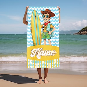 May include: A rectangular beach towel featuring a cartoon character wearing a brown cowboy hat, sunglasses, and a red neckerchief, holding a yellow and blue surfboard. The background has a light blue wave pattern and a yellow banner with the word Name.