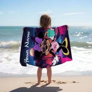 Pu&ograve; includere: Un telo mare con un personaggio dei cartoni animati con occhiali da sole, un fiocco viola e una bevanda. L'asciugamano ha un design vivace con il testo "Your Name" in bianco, su uno sfondo di tramonto e palme.
