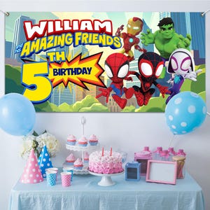 Puede incluir: Una escena de fiesta de cumplea&ntilde;os con una pancarta con superh&eacute;roes de dibujos animados y el texto "WILLIAM and his AMAZING FRIENDS 5TH BIRTHDAY". Una tarta, cupcakes, globos y art&iacute;culos de fiesta est&aacute;n sobre una mesa.
