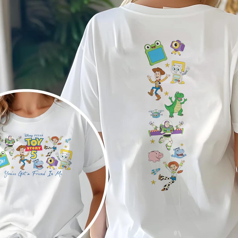 May include: A white t-shirt featuring Toy Story 5 graphics. The front displays the Toy Story 5 logo with characters and the text "You've Got a Friend In Me." The back shows a vertical arrangement of various Toy Story characters including Woody, Buzz Lightyear, Rex, and Jessie.