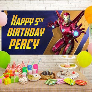 Puede incluir: Una escena de fiesta de cumplea&ntilde;os con una pancarta de Iron Man y el texto "Happy 5th Birthday Percy". Globos de varios colores rodean una mesa con regalos, pastel y golosinas. Tambi&eacute;n se ven gorros de fiesta y bebidas.