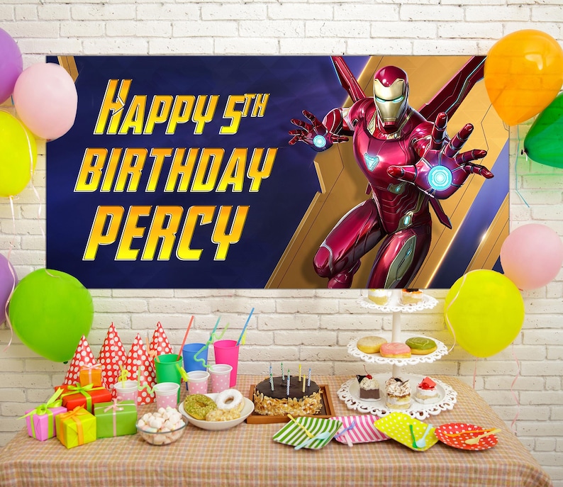 Puede incluir: Una escena de fiesta de cumplea&ntilde;os con una pancarta de Iron Man y el texto "Happy 5th Birthday Percy". Globos de varios colores rodean una mesa con regalos, pastel y golosinas. Tambi&eacute;n se ven gorros de fiesta y bebidas.