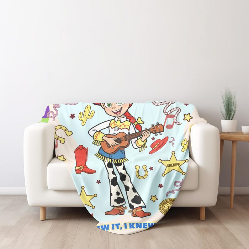 May include: A light blue throw blanket featuring a cartoon cowgirl with red hair playing a ukulele, surrounded by patterns of red cowboy boots, yellow sheriff stars, horseshoes, and cacti, with the text "KNEW IT, I KNEW IT" at the bottom.