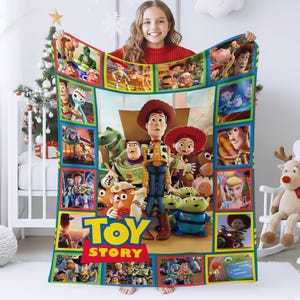 May include: A rectangular fleece blanket featuring a collage of various Toy Story characters including Woody, Buzz Lightyear, Jessie, and the Aliens. The blanket has a large Toy Story logo at the bottom and is framed by a colorful border of smaller scenes.
