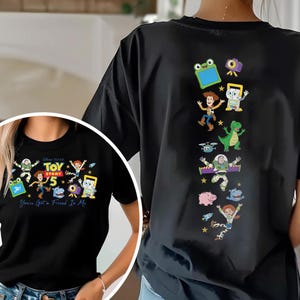 May include: A black t-shirt featuring Toy Story 5 graphics. The front displays the Toy Story 5 logo, characters, and the text "You've Got a Friend In Me." The back features a vertical arrangement of various Toy Story character illustrations.