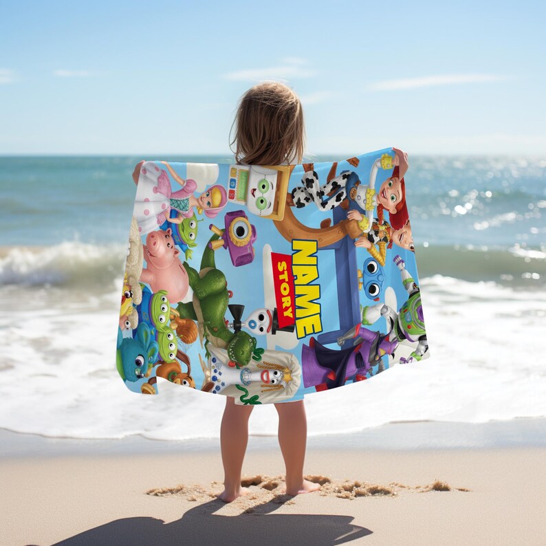 May include: A rectangular beach towel featuring a vibrant blue background with various Toy Story character illustrations, including Rex, Hamm, and Buzz Lightyear. The center displays the text NAME STORY in bold yellow and red block lettering.