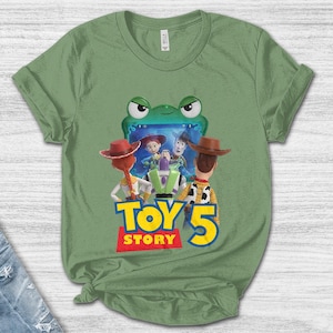 May include: Green t-shirt featuring a graphic of characters from the movie Toy Story 5. The design includes Woody, Buzz Lightyear, and Jessie, with the words "Toy Story 5" in a colorful font. The shirt is made of a soft material.