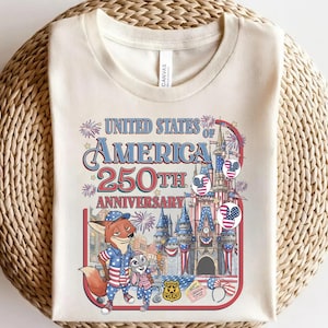 Puede incluir: Camiseta color crema con un gr&aacute;fico colorido que celebra el 250 aniversario de los Estados Unidos de Am&eacute;rica. El dise&ntilde;o incluye personajes de dibujos animados, fuegos artificiales y un castillo, con el texto "United States of America 250th Anniversary."