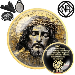 Puede incluir: Una moneda dorada con una imagen de estilo mosaico de Jesús con una corona de espinas. La moneda tiene un borde negro con el texto "Dios, concédeme la serenidad..." y el logotipo de NA. También se incluyen un soporte negro y un colgante.
