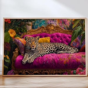 May include: A framed print featuring a leopard resting on a vibrant pink sofa with gold accents. The sofa is adorned with colorful pillows, and the background showcases lush greenery and floral elements, creating a luxurious and exotic scene.