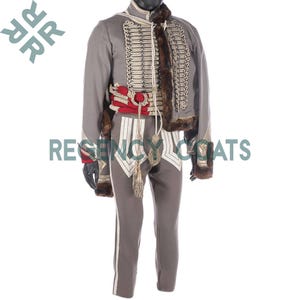 Puede incluir: Un uniforme gris de estilo militar con una chaqueta con adornos dorados, cuello de piel y múltiples filas de botones. El conjunto incluye pantalones a juego con rayas blancas y un cinturón rojo. El texto "REGENCY COATS" es visible.