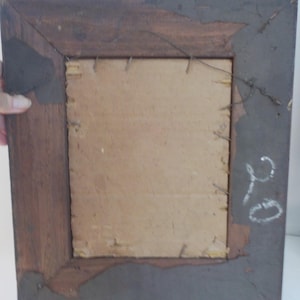 K&ouml;nnte beinhalten: Ein dunkelbrauner Holzbildrahmen mit einem Kartonr&uuml;cken. Der Rahmen hat ein schlichtes Design und ist in gutem Zustand. Auf der R&uuml;ckseite des Rahmens ist eine handgeschriebene Nummer "210" mit wei&szlig;er Kreide.