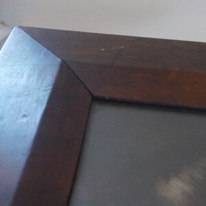 K&ouml;nnte beinhalten: Ein dunkelbrauner Holzrahmen mit einer grauen Passepartout und einem hellgrauen Hintergrund.