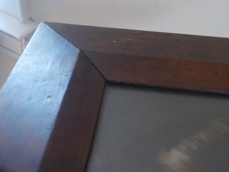 K&ouml;nnte beinhalten: Ein dunkelbrauner Holzrahmen mit einer grauen Passepartout und einem hellgrauen Hintergrund.