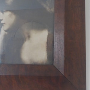 K&ouml;nnte beinhalten: Nahaufnahme der rechten unteren Ecke eines dunklen Holzbildrahmens.