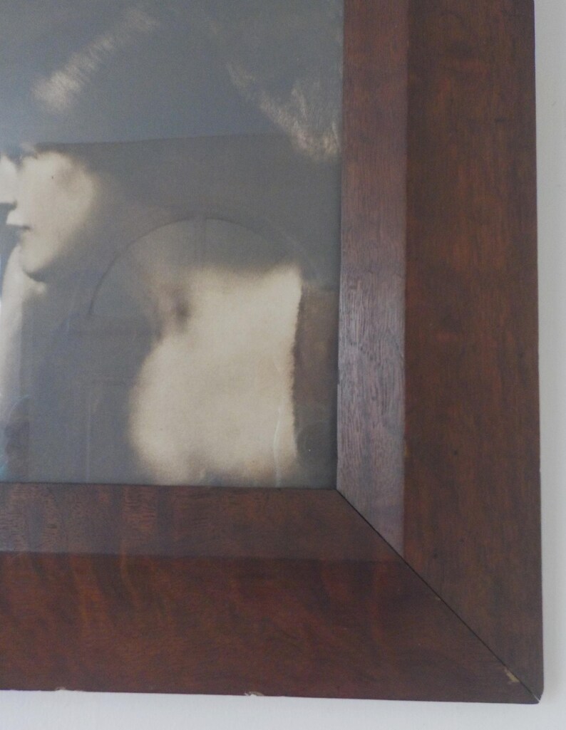 K&ouml;nnte beinhalten: Nahaufnahme der rechten unteren Ecke eines dunklen Holzbildrahmens.