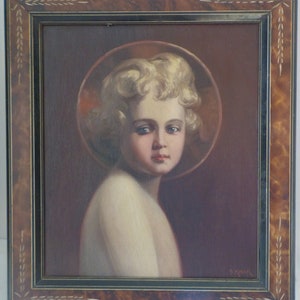 May include: A framed oil painting of a young child with blonde hair and blue eyes. The child is wearing a white robe and has a halo around their head. The painting is set against a dark brown background.