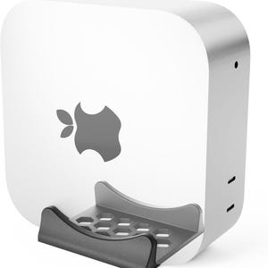 May include: A white computer with a gray Apple logo and a dark gray stand. The computer has a rounded rectangular shape with a smooth, glossy finish. The stand is designed to hold the computer securely.