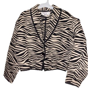 May include: A cropped zebra-print jacket with black trim and a single button closure. The jacket features a cream-colored background with black stripes, a notched collar, and long sleeves. The label reads "YWGIRL".