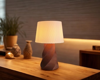 May include: A table lamp with a white, textured lampshade and a brown, twisted base. The lamp is turned on and illuminating the room.