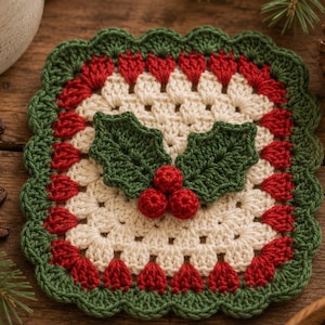 May include: A square crochet coaster featuring a cream-coloured centre, a red and green border with a scalloped edge, and a central appliqué of two dark green crocheted holly leaves paired with three small, round, red crocheted berries.