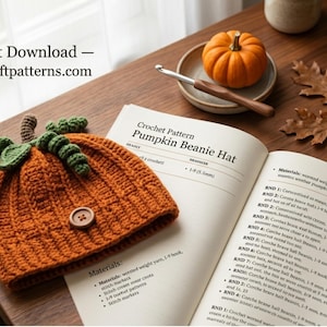 May include: A crocheted orange pumpkin beanie hat with a brown button and green leaves, displayed next to an open instruction manual titled Crochet Pattern Pumpkin Beanie Hat, with text reading Instant Download — easycraftpatterns.com.