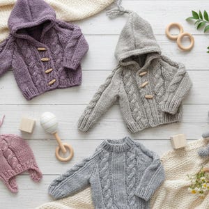 May include: A collection of knitted baby apparel including a purple hooded cardigan, a grey hooded cardigan, and a grey sweater, all featuring cable knit patterns and wooden toggle buttons, accompanied by a pink knit hat and a grey crochet elephant.