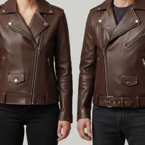 May include: Two brown leather jackets with asymmetrical zippers, notched lapels, and snap-closure pockets. The jackets have a belted waist and are worn with black jeans and a dark shirt.