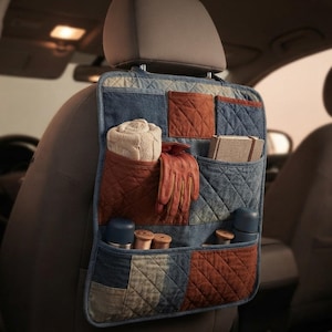 May include: A rectangular car seat back organiser featuring a quilted patchwork design in shades of blue and rust orange. It includes multiple pockets containing a rolled white knit fabric, brown leather gloves, a notebook, and small cylindrical items.