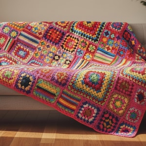 May include: A handmade crochet blanket featuring a vibrant patchwork of multicolored granny squares and striped rectangular blocks. The textile is composed of various yarn colors including red, yellow, blue, green, and purple, finished with a pink border.