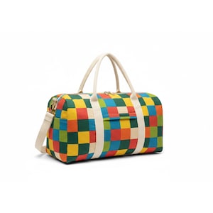 Op de afbeelding: Een kleurrijke duffeltas met een levendig dambordpatroon in rood, geel, groen en blauw. De tas heeft crèmekleurige handvatten en een schouderriem. De tas is ontworpen voor reizen en vrije tijd.