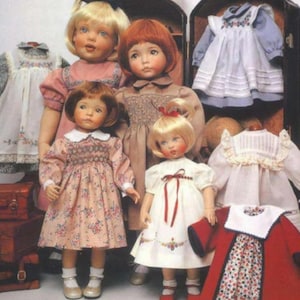 May include: Four porcelain dolls with painted facial features and hair, dressed in various outfits including floral and solid dresses. They are surrounded by miniature clothing items, including a red coat and white dresses, stacked atop vintage suitcases.