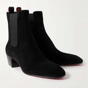 May include: Black suede ankle boots with a pointed toe and a low block heel. The boots feature a red sole and a pull tab. These boots are a classic style.