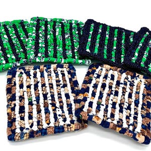 May include: Set of six woven pot holders. Four are green and black with a white polka dot pattern. Two are white, brown, and blue with a striped pattern.