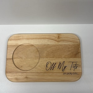 May include: Wooden serving tray with a circular recess for a glass. The tray features the etched text "Off My Tits" and "on picky bits...". The wood grain is visible on the rectangular tray.